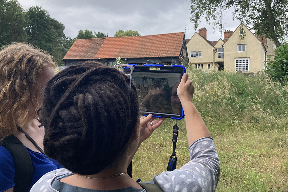 Two people viewing 'The Glebe Farm' print using augmented reality in situ