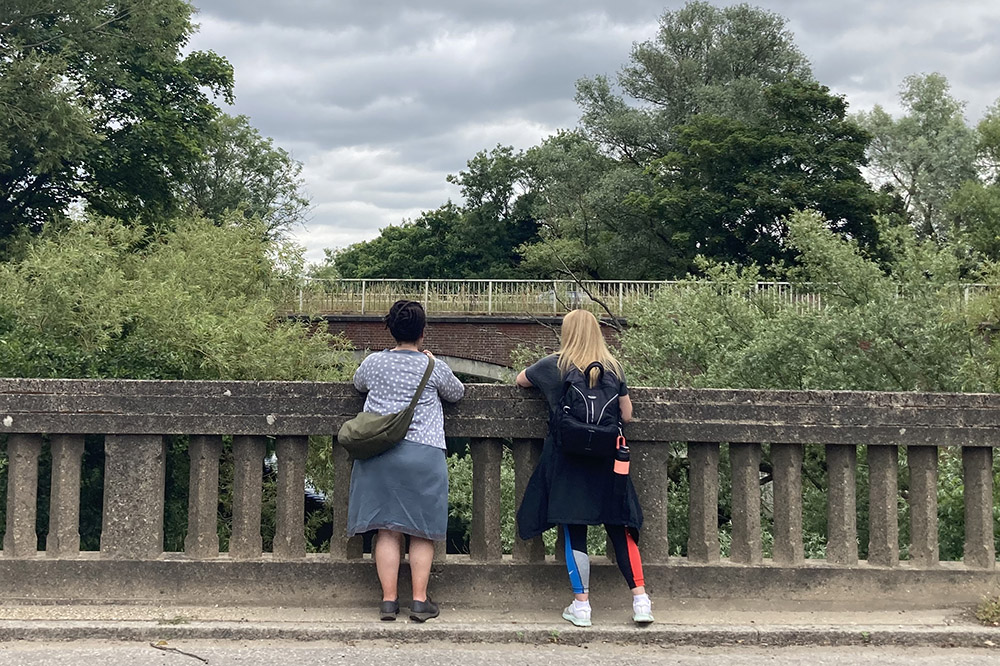 Two fellow walkers stop and look at the bridges and river weaving in the landscape